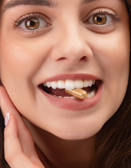 Woman with a capsule between her teeth